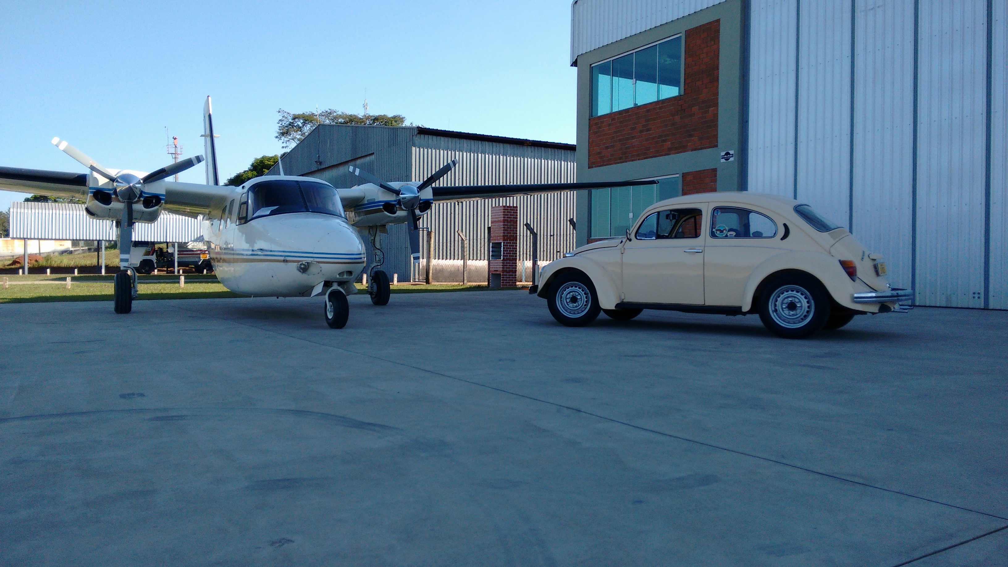 fusca amarelo ao lado de um avião